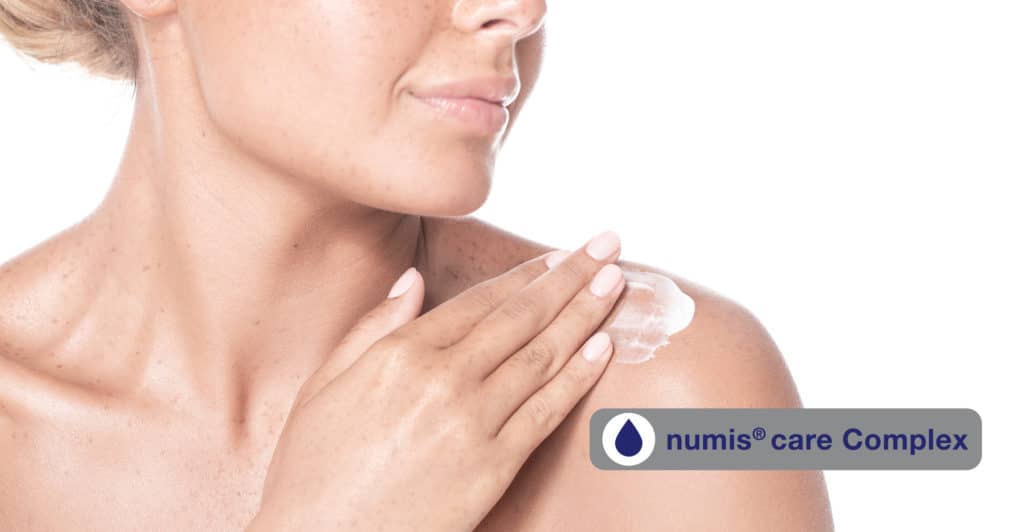 Frau, die sich die Schulter eincremt mit numis® Care Complex