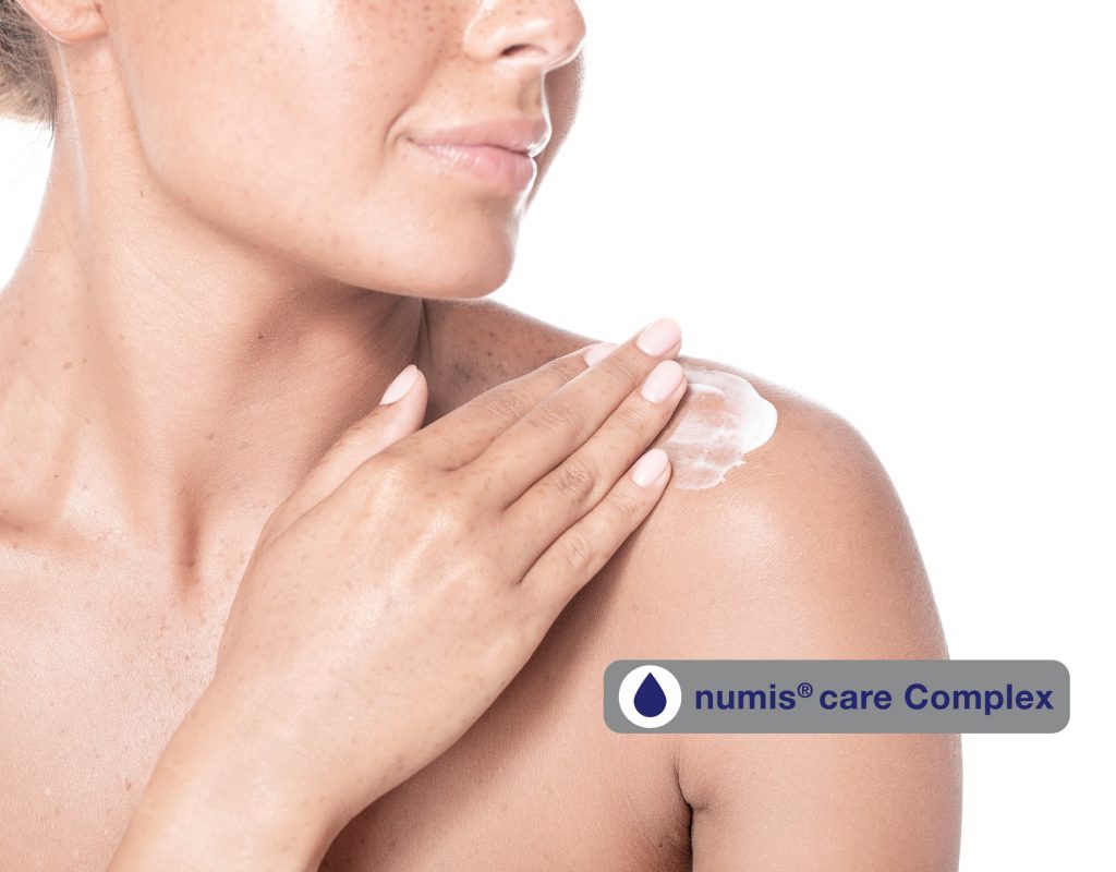Frau, die sich die Schulter eincremt und numis® Care Complex